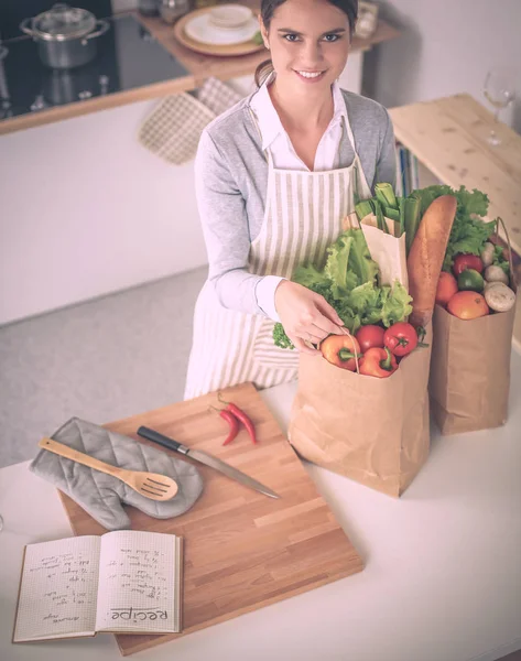 Mujer con bolsas de compras en la cocina en casa, de pie cerca del escritorio — Foto de Stock