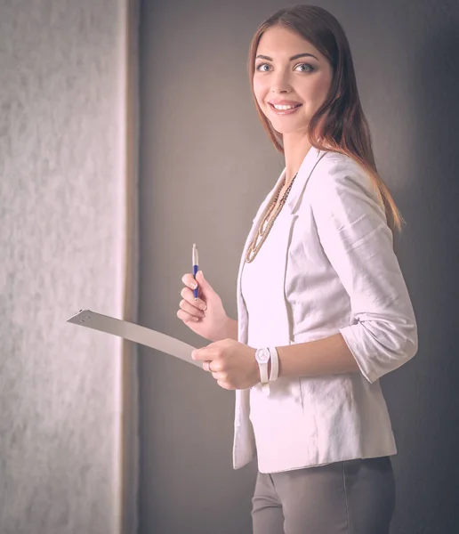 Young woman holding a laptop, standing on gray background — Stock Photo, Image