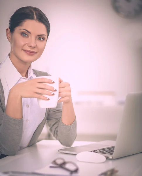 Joven mujer de negocios sentada en el escritorio con taza en la oficina — Foto de Stock