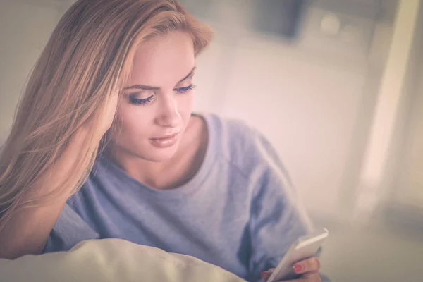 Mujer bonita en su sala de estar acostada en el sofá enviando un mensaje — Foto de Stock