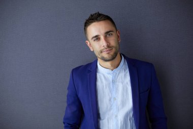 Gri arka planda yalnız oturan genç iş adamı.