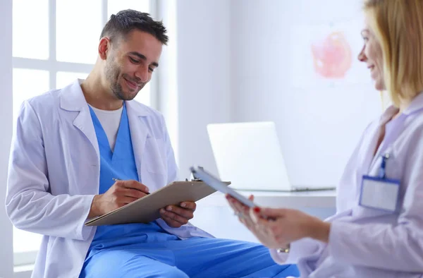 Handsome doctor is talking with young female doctor and making n — Stock Photo, Image