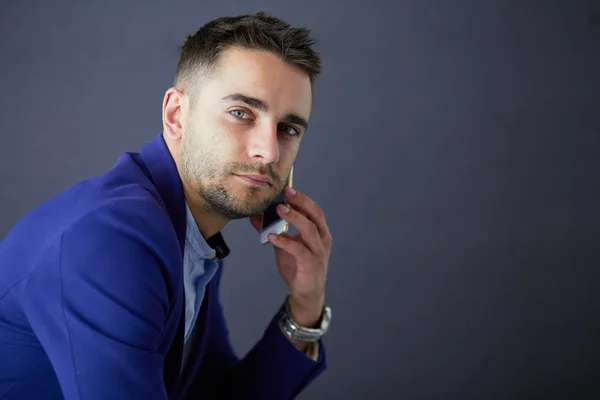 Young businessman sitting isolated on grey background. — Stock Photo, Image