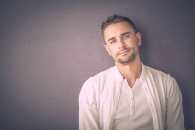 Gri arka planda yalnız oturan genç iş adamı.