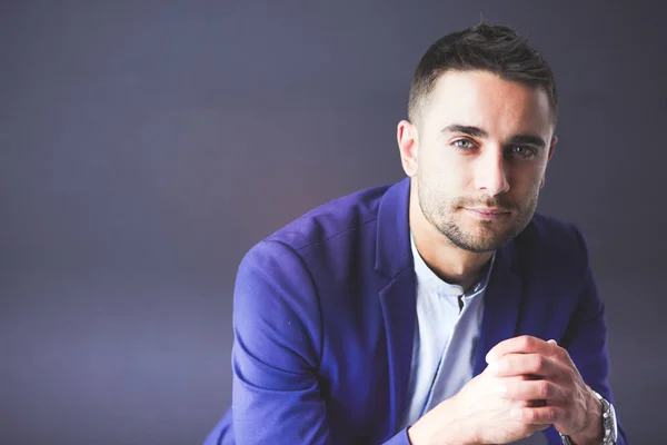 Joven empresario sentado aislado sobre fondo gris. —  Fotos de Stock