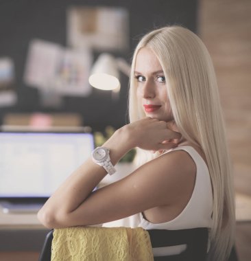 Moda tasarımcıları stüdyoda çalışıyor. Masanın üzerinde oturuyorlar.