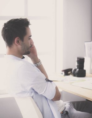 İnternette çalışırken bilgisayarın ve dizüstü bilgisayarın önünde grafik stüdyosunda oturan genç tasarımcının portresi