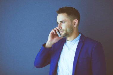 Gri arka planda yalnız oturan genç iş adamı.