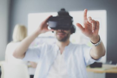 Genç erkek yazılım programcısı ofiste üç boyutlu sanal gerçeklik gözlükleriyle yeni bir uygulama test ediyor..