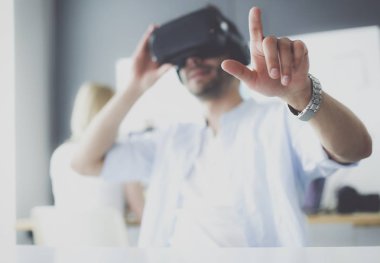 Genç erkek yazılım programcısı ofiste üç boyutlu sanal gerçeklik gözlükleriyle yeni bir uygulama test ediyor..