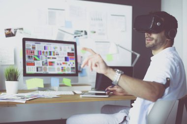 Genç erkek yazılım programcısı ofiste üç boyutlu sanal gerçeklik gözlükleriyle yeni bir uygulama test ediyor..