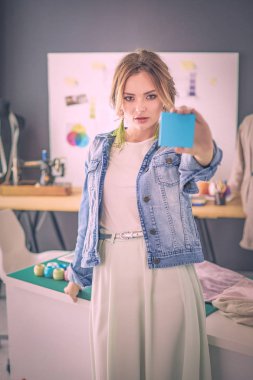 Moda tasarımcısı kadın stüdyoda tasarımları üzerinde çalışıyor.