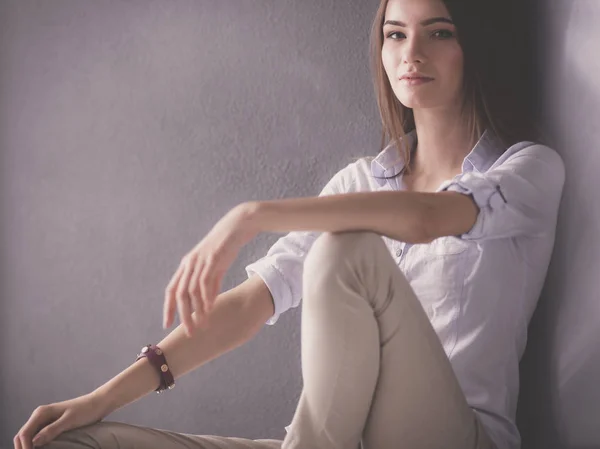 Young woman sitting on the floor near dark wall — Stock Photo, Image