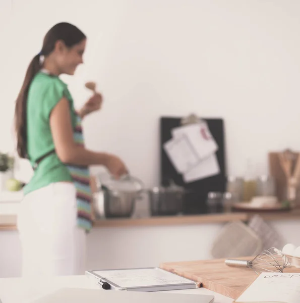 Jeune femme souriante dans la cuisine, isolée sur le fond — Photo