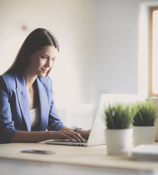 Femme assise sur le bureau avec ordinateur portable — Photo