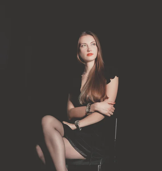 Vacker kvinna sitter en stol, isolerad på svart bakgrund. Vacker kvinna — Stockfoto
