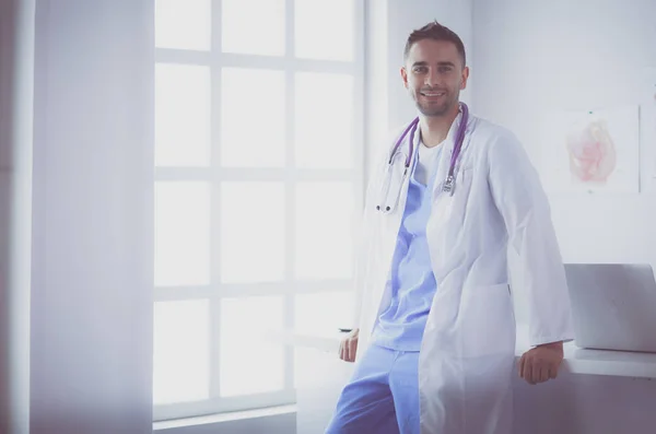 Retrato médico masculino joven y confiado de pie en el consultorio médico. — Foto de Stock