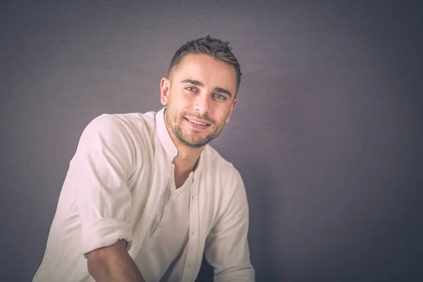 Joven empresario sentado aislado sobre fondo gris. —  Fotos de Stock