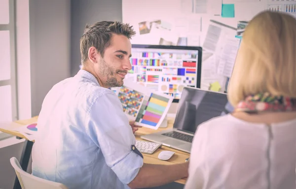 Porträtt av ung designer sitter i grafisk studio framför bärbar dator och dator när du arbetar online. — Stockfoto