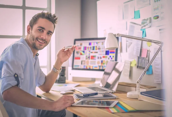 Porträt eines jungen Designers, der im Grafikstudio vor Laptop und Computer sitzt, während er online arbeitet. — Stockfoto