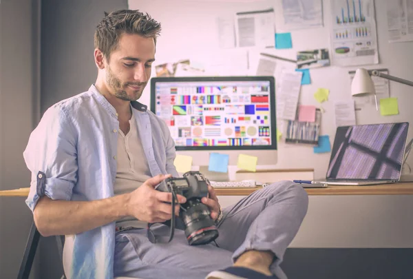 Portrét mladého návrháře sedícího v grafickém studiu před notebookem a počítačem při práci online. — Stock fotografie