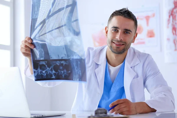 El guapo doctor está hablando con una paciente joven y tomando notas mientras está sentado en su consultorio.. — Foto de Stock