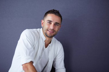 Gri arka planda yalnız oturan genç iş adamı.