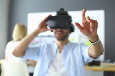 Genç erkek yazılım programcısı ofiste üç boyutlu sanal gerçeklik gözlükleriyle yeni bir uygulama test ediyor..