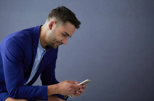 Joven empresario sentado aislado sobre fondo gris. —  Fotos de Stock