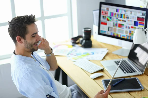 Porträt eines jungen Designers, der im Grafikstudio vor Laptop und Computer sitzt, während er online arbeitet. — Stockfoto