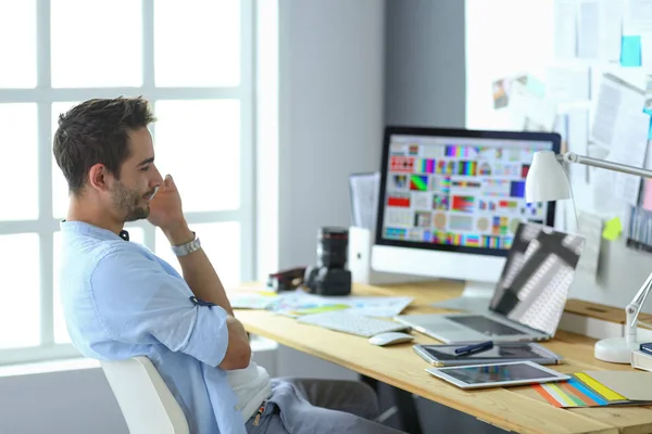 Porträt eines jungen Designers, der im Grafikstudio vor Laptop und Computer sitzt, während er online arbeitet. — Stockfoto