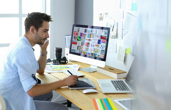 Πορτρέτο του νεαρού σχεδιαστή που κάθεται στο γραφιστικό στούντιο μπροστά από το laptop και τον υπολογιστή ενώ εργάζεται στο διαδίκτυο. — Φωτογραφία Αρχείου