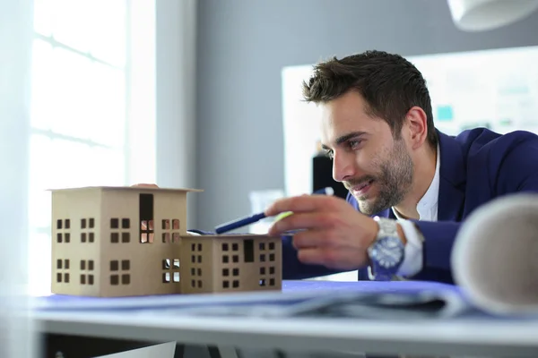 Homme d'affaires tenant maison miniature à portée de main debout dans le bureau . — Photo