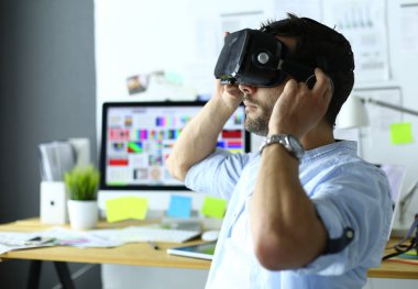 Genç erkek yazılım programcısı ofiste üç boyutlu sanal gerçeklik gözlükleriyle yeni bir uygulama test ediyor..