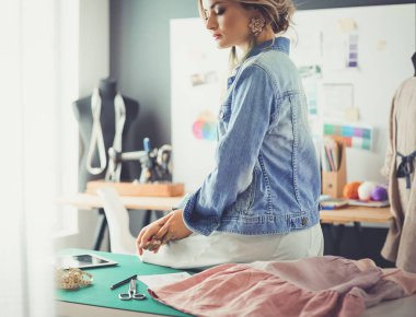 Moda tasarımcısı kadın stüdyoda tasarımları üzerinde çalışıyor.