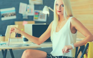 Moda tasarımcıları stüdyoda çalışıyor. Masanın üzerinde oturuyorlar.