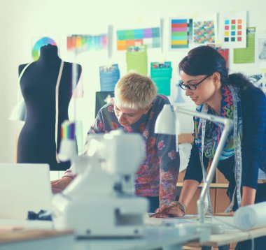 Genç terzi kâğıt üzerinde kıyafet deseni tasarlıyor.