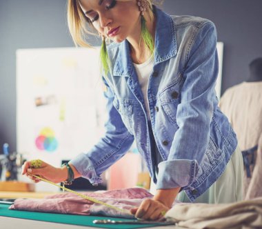Moda tasarımcısı kadın stüdyoda tasarımları üzerinde çalışıyor.