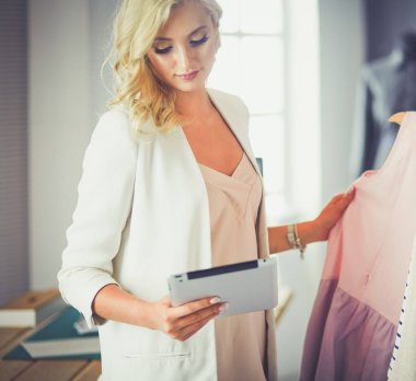 Moda tasarımcısı kadın stüdyoda tasarımları üzerinde çalışıyor.