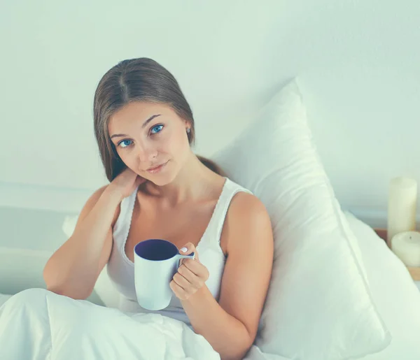 年轻漂亮的女人在床上享受一杯茶 — 图库照片