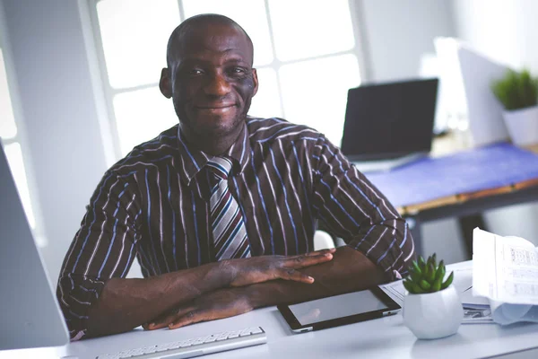 Guapo afroamericano hombre de negocios en traje clásico está utilizando un ordenador portátil y sonriendo mientras trabaja en la oficina —  Fotos de Stock