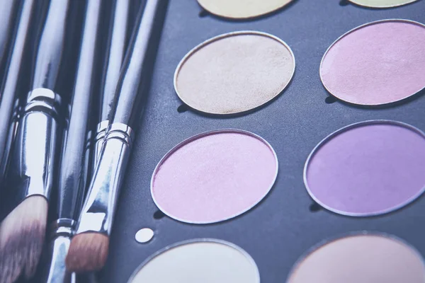 Makeup brushes and make-up eye shadows on desk — Stock Photo, Image