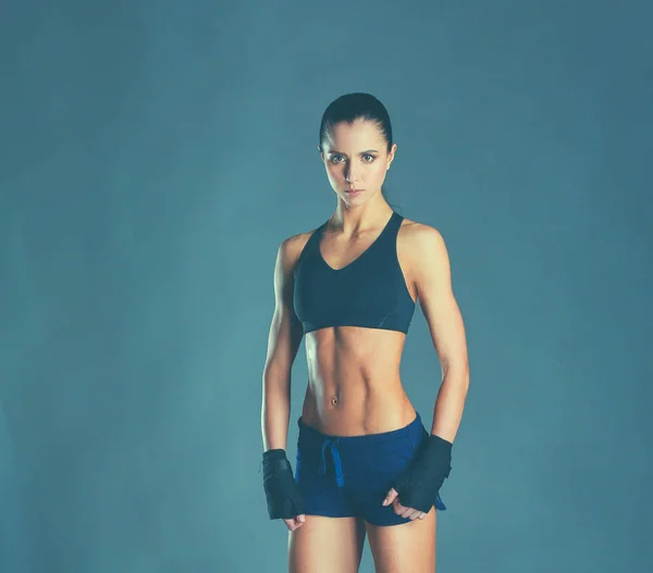 Muscular young woman posing in sportswear against black background — Stock Photo, Image