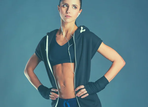 Muskulös ung kvinna poserar i sportkläder mot svart bakgrund — Stockfoto