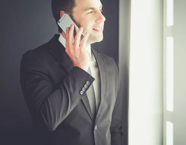Hombre de negocios guapo hablando en el teléfono móvil en la oficina moderna. —  Fotos de Stock