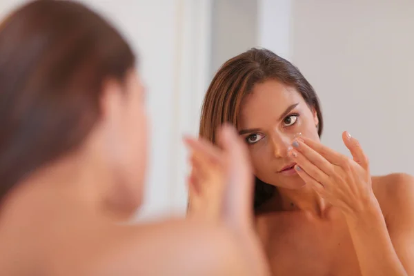 Attractive young woman applying cream on her Face