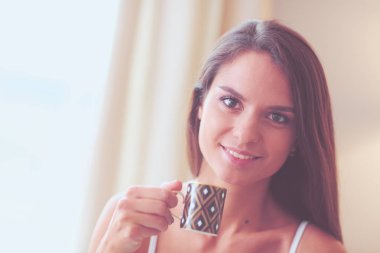 bir bardak süt ile yatakta oturan genç kadın.