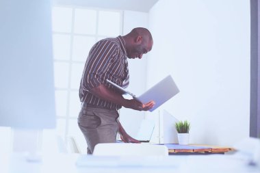 Ofiste bilgisayar ve planlarla çalışan Afrikalı Amerikalı bir mimar.