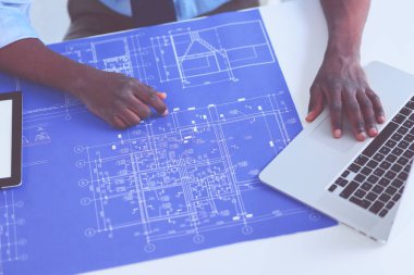 Ofiste bilgisayar ve planlarla çalışan Afrikalı Amerikalı bir mimar.