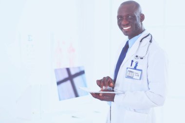 Tablet bilgisayarlı siyahi bir doktor hastanede bekliyor.